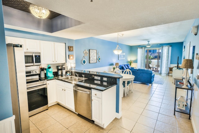 kitchen with ceiling fan with notable chandelier, white cabinetry, kitchen peninsula, stainless steel appliances, and sink