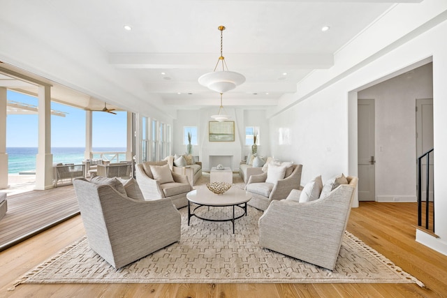 living room with a healthy amount of sunlight, a water view, and light hardwood / wood-style floors