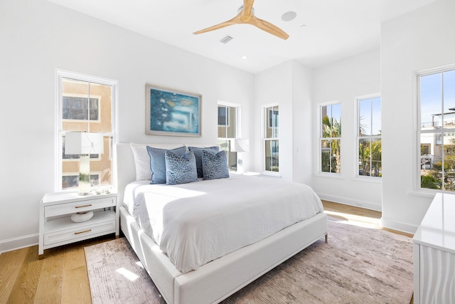 bedroom with light hardwood / wood-style flooring, ceiling fan, and multiple windows