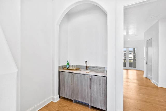 bar featuring sink, french doors, and light wood-type flooring