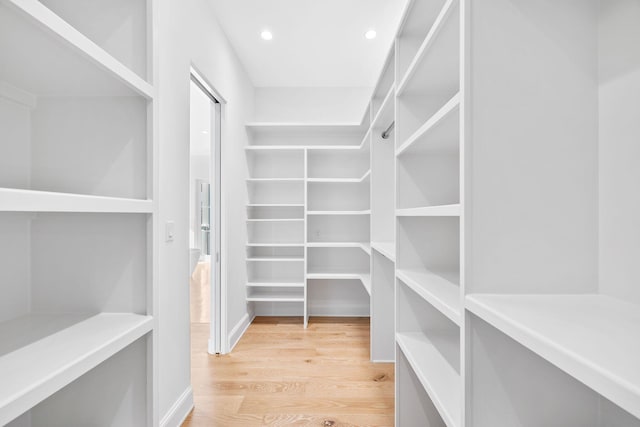 walk in closet with light hardwood / wood-style flooring