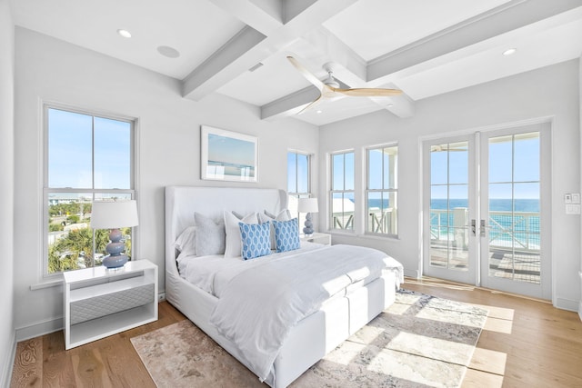 bedroom with beamed ceiling, light hardwood / wood-style flooring, french doors, and ceiling fan