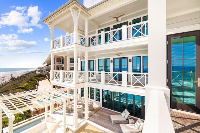 back of property with ceiling fan, a water view, and a balcony