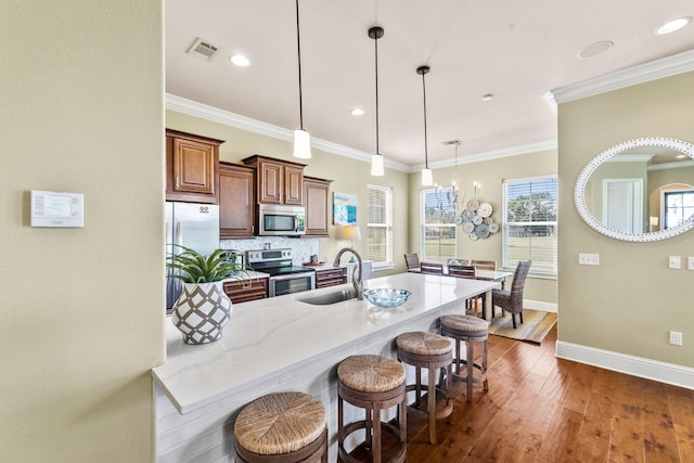 kitchen featuring pendant lighting, dark wood-type flooring, stainless steel appliances, sink, and light stone counters