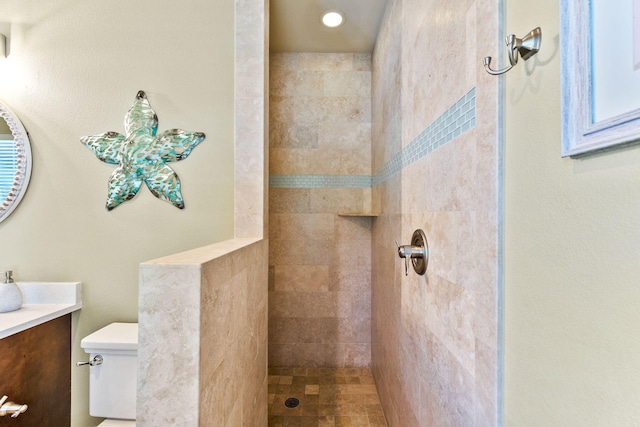 bathroom with tiled shower, vanity, and toilet