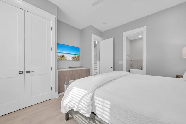 bedroom with connected bathroom, light hardwood / wood-style floors, and ceiling fan