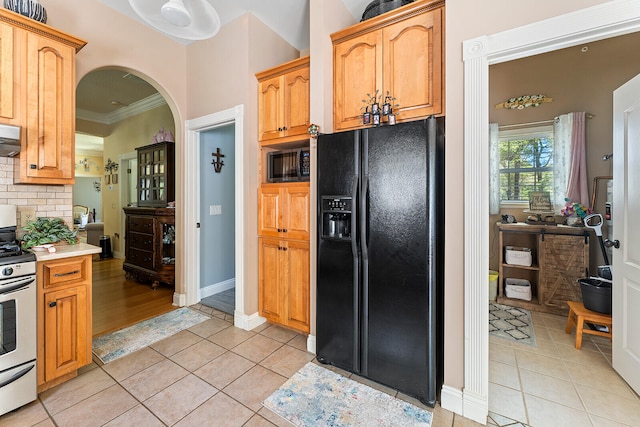 kitchen with ventilation hood, light hardwood / wood-style flooring, black appliances, ornamental molding, and tasteful backsplash