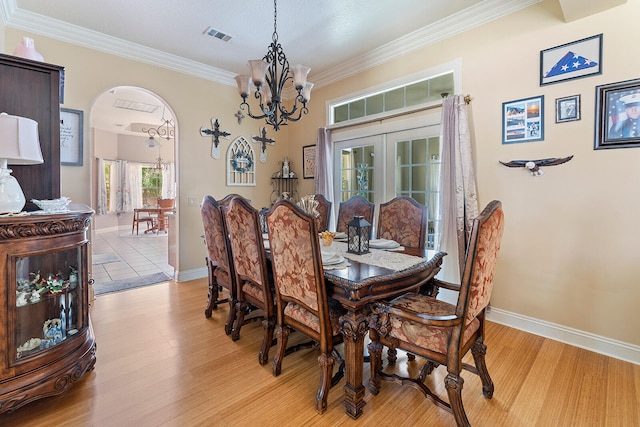 dining area featuring a chandelier, crown molding, french doors, and light wood-type flooring