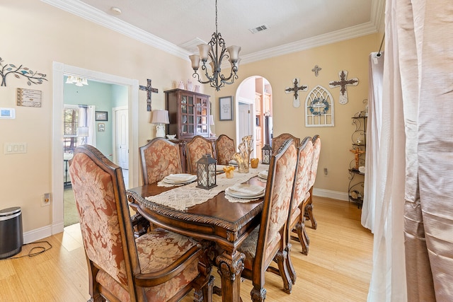 dining space featuring ornamental molding, light hardwood / wood-style flooring, and an inviting chandelier