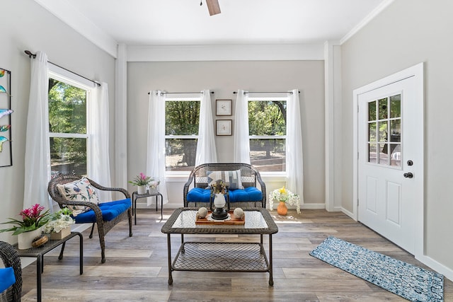 living area with ornamental molding, light wood-type flooring, and a wealth of natural light