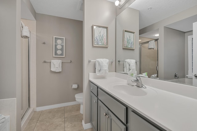 bathroom with a textured ceiling, tile floors, toilet, and vanity with extensive cabinet space