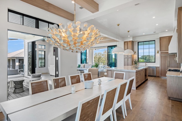 dining space with beam ceiling, a notable chandelier, and light wood-type flooring