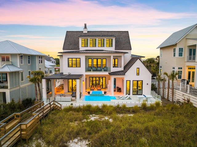 back house at dusk with french doors, an outdoor living space, and a patio area