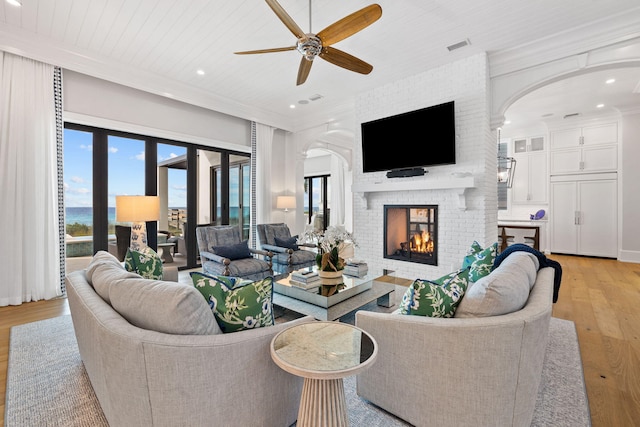 living room with a water view, light hardwood / wood-style flooring, a fireplace, and ornamental molding