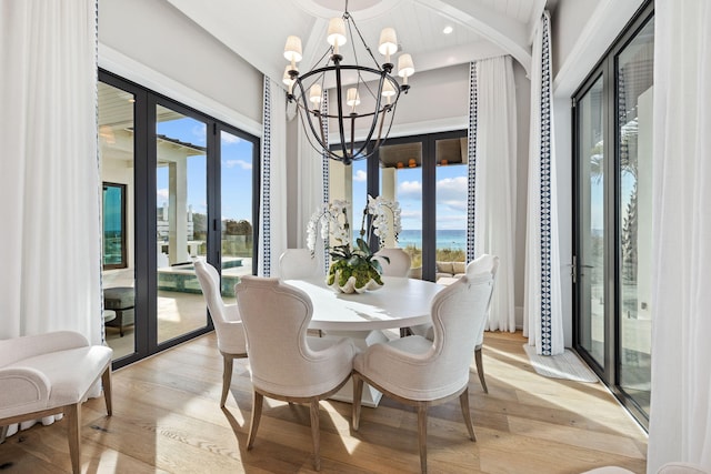 dining space with a notable chandelier, light hardwood / wood-style flooring, and a water view