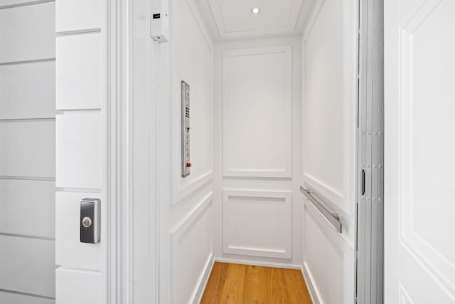 interior space with light wood-type flooring, elevator, and ornamental molding