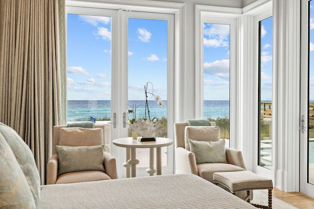 bedroom with light hardwood / wood-style flooring, a water view, french doors, and multiple windows