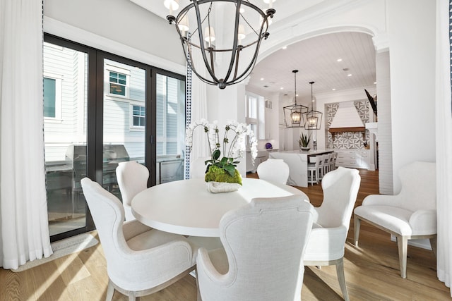 dining room with a healthy amount of sunlight, light hardwood / wood-style floors, and an inviting chandelier