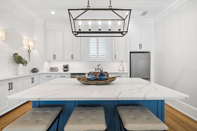 kitchen with high end fridge, crown molding, a breakfast bar area, and light stone countertops