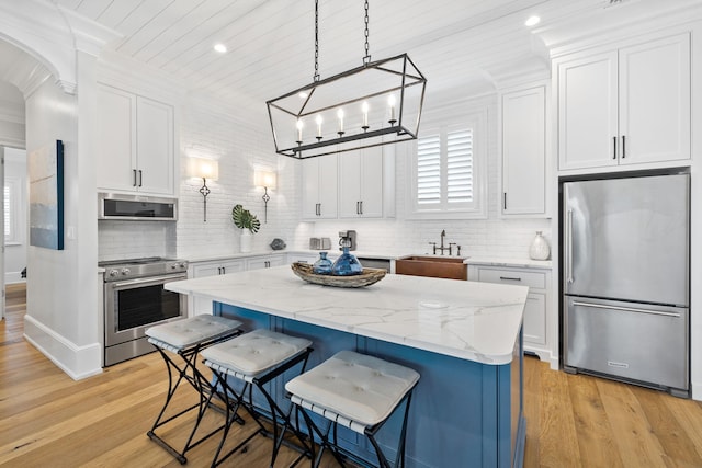 kitchen featuring tasteful backsplash, appliances with stainless steel finishes, white cabinets, and light wood-type flooring