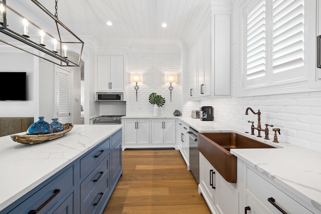 kitchen with light stone counters, light hardwood / wood-style floors, backsplash, white cabinetry, and hanging light fixtures