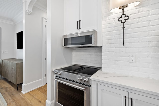 kitchen with stainless steel appliances, light stone countertops, light hardwood / wood-style floors, and white cabinetry