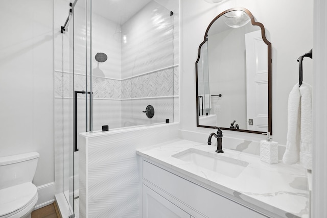 bathroom featuring a shower with shower door, toilet, and oversized vanity