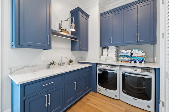 laundry room with washing machine and dryer, cabinets, sink, light wood-type flooring, and ornamental molding