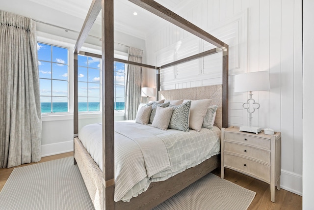 bedroom featuring hardwood / wood-style floors and a water view