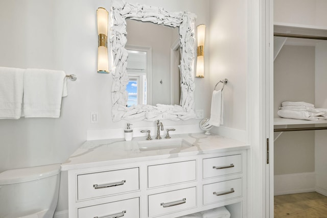 bathroom featuring tile flooring, vanity, and toilet