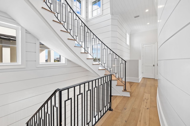 stairs featuring ornamental molding and light hardwood / wood-style flooring