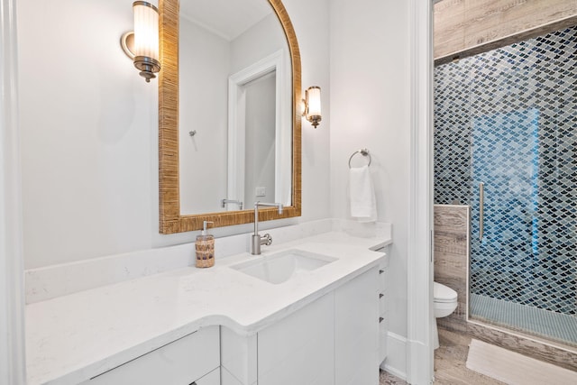 bathroom with wood-type flooring, vanity with extensive cabinet space, and toilet