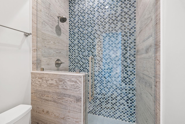 bathroom with tiled shower and toilet