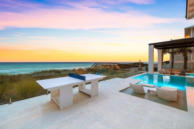 pool at dusk with a water view and a patio area