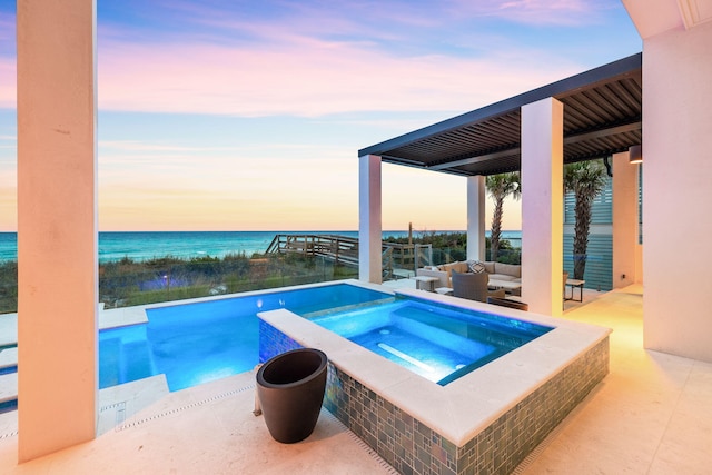 pool at dusk with a water view and an in ground hot tub