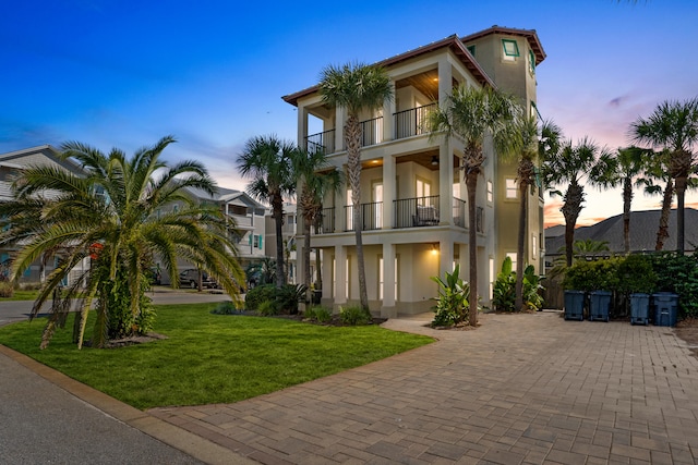 mediterranean / spanish-style home featuring a balcony and a lawn