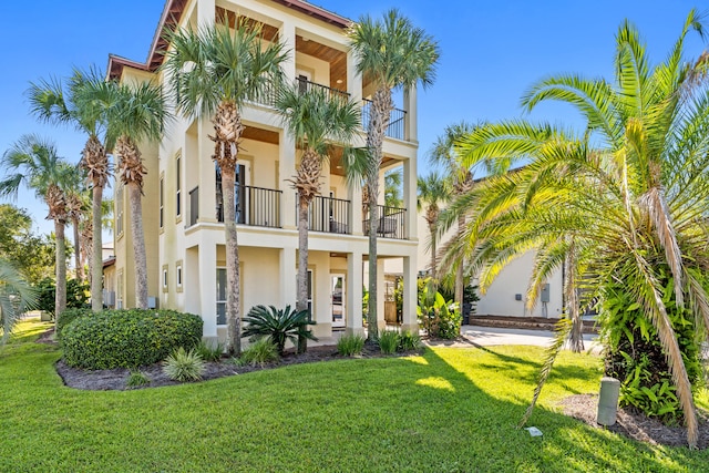 view of front facade with a balcony and a front yard