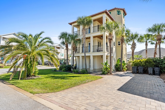 view of front of house featuring a balcony and a front lawn