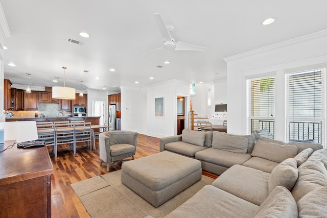 living room featuring crown molding, light hardwood / wood-style flooring, and ceiling fan