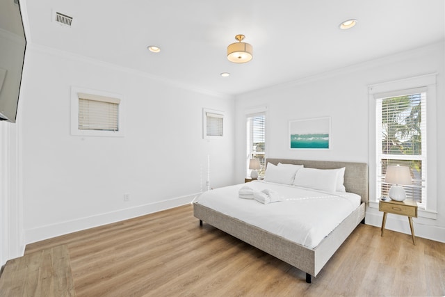 bedroom with light hardwood / wood-style floors and crown molding