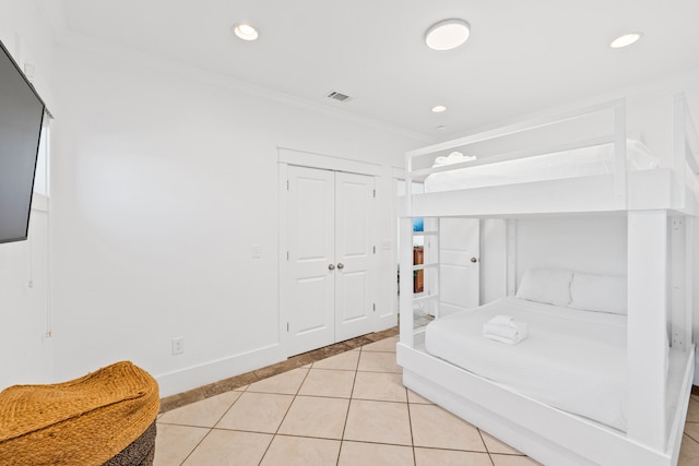 bedroom with ornamental molding, a closet, and light tile flooring