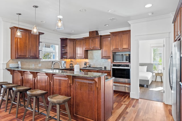 kitchen featuring hardwood / wood-style flooring, appliances with stainless steel finishes, decorative light fixtures, and backsplash