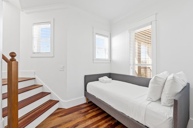 bedroom featuring dark hardwood / wood-style flooring, multiple windows, and crown molding