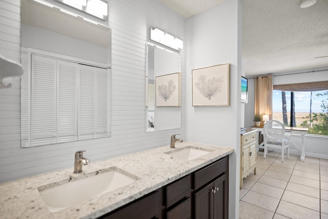 bathroom with tile patterned floors, double vanity, a textured ceiling, and a sink