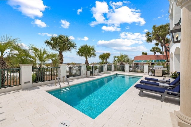 view of pool featuring a fenced in pool, a patio area, and grilling area