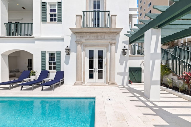 exterior space featuring a pergola, a fenced in pool, a patio, french doors, and a balcony