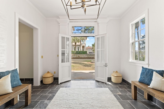 doorway to outside with ornamental molding, dark tile flooring, and an inviting chandelier