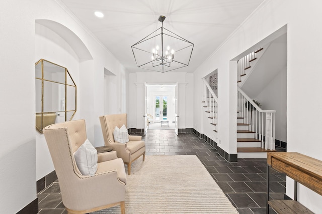 sitting room with ornamental molding, dark tile floors, and a notable chandelier