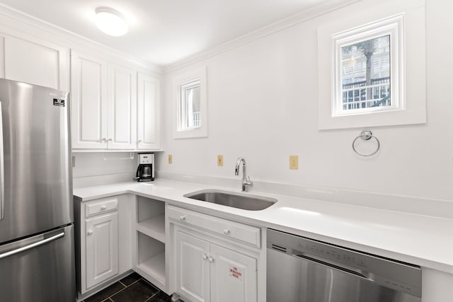 kitchen featuring dark tile floors, white cabinets, ornamental molding, appliances with stainless steel finishes, and sink