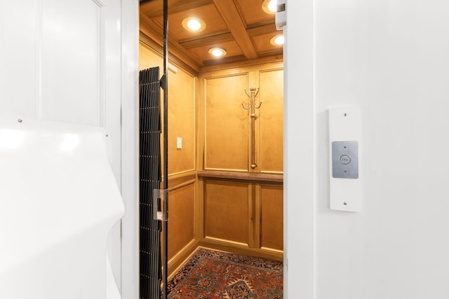 interior details with coffered ceiling, elevator, and beamed ceiling